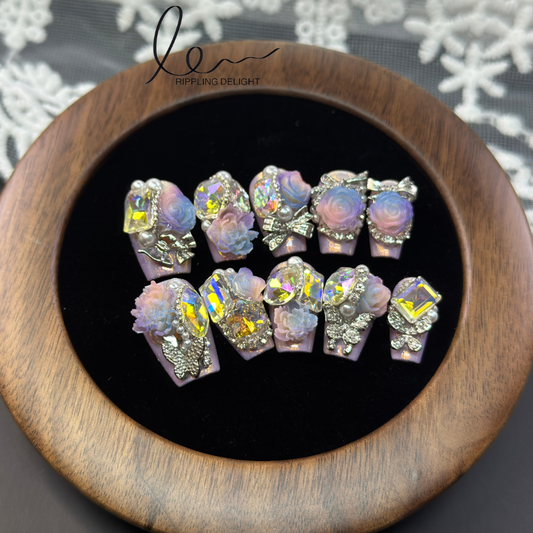 （Medium Coffin press-on nails）Handmade press-on nails with a pink base of fine glitter, colorful rhinestone inlays and floral accessories.